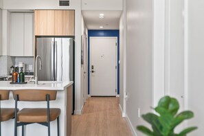 A modern kitchen with a stainless steel refrigerator, a sink, and bar stools.