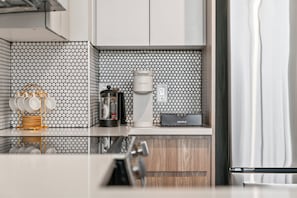 A modern kitchen with a coffee maker, a kettle, and a kettle warmer on the counter. - King Bed | Gym |Resort Style Pool | Minutes to Beach | Pet Friendly |Pickle Ball (Fort Lauderdale)