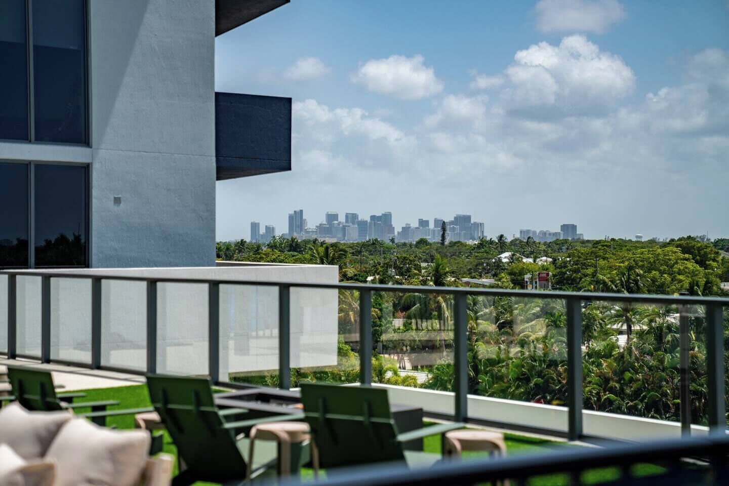 Un balcon avec des chaises vertes et une vue sur les bâtiments d’une ville.