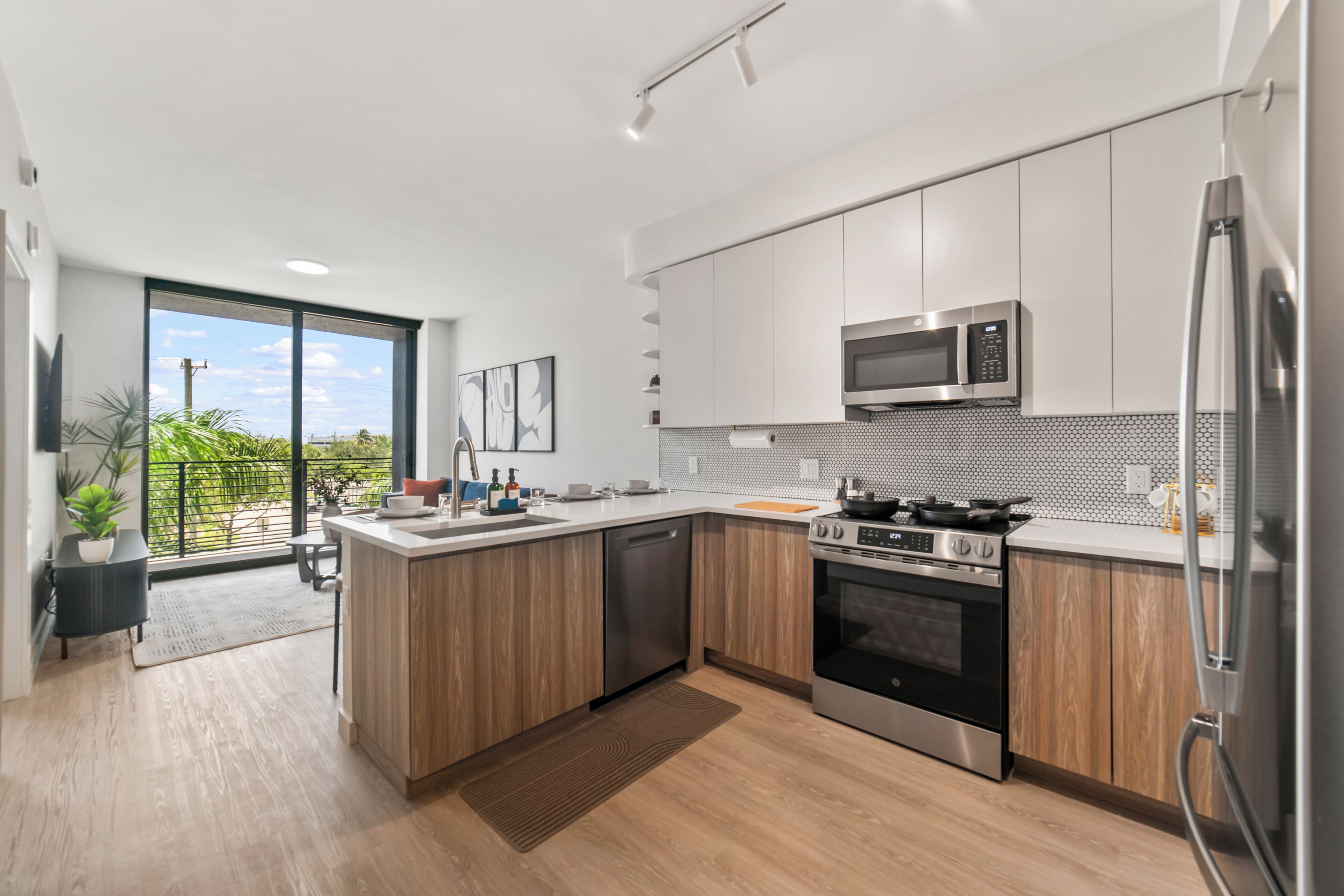 A modern kitchen with a central island, stainless steel appliances, and a view to the outdoors.