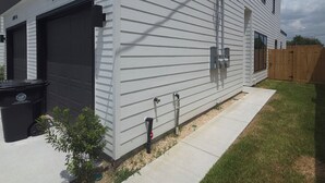 Ein modernes, zweistöckiges Haus mit Garage, kleinem Vorgarten und Holzzaun.