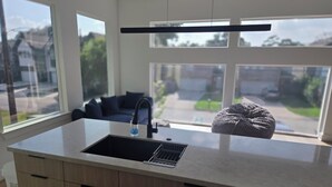 Eine moderne Küche mit großem Fenster, integriertem Spülbecken und Arbeitsplatte.