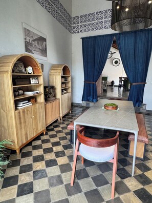 A dining area with a checkered floor, a table with chairs, and two wooden cabinets with shelves. - NEW Designer Colonial  2-bedroom boutique in the core of Granada (Granada)