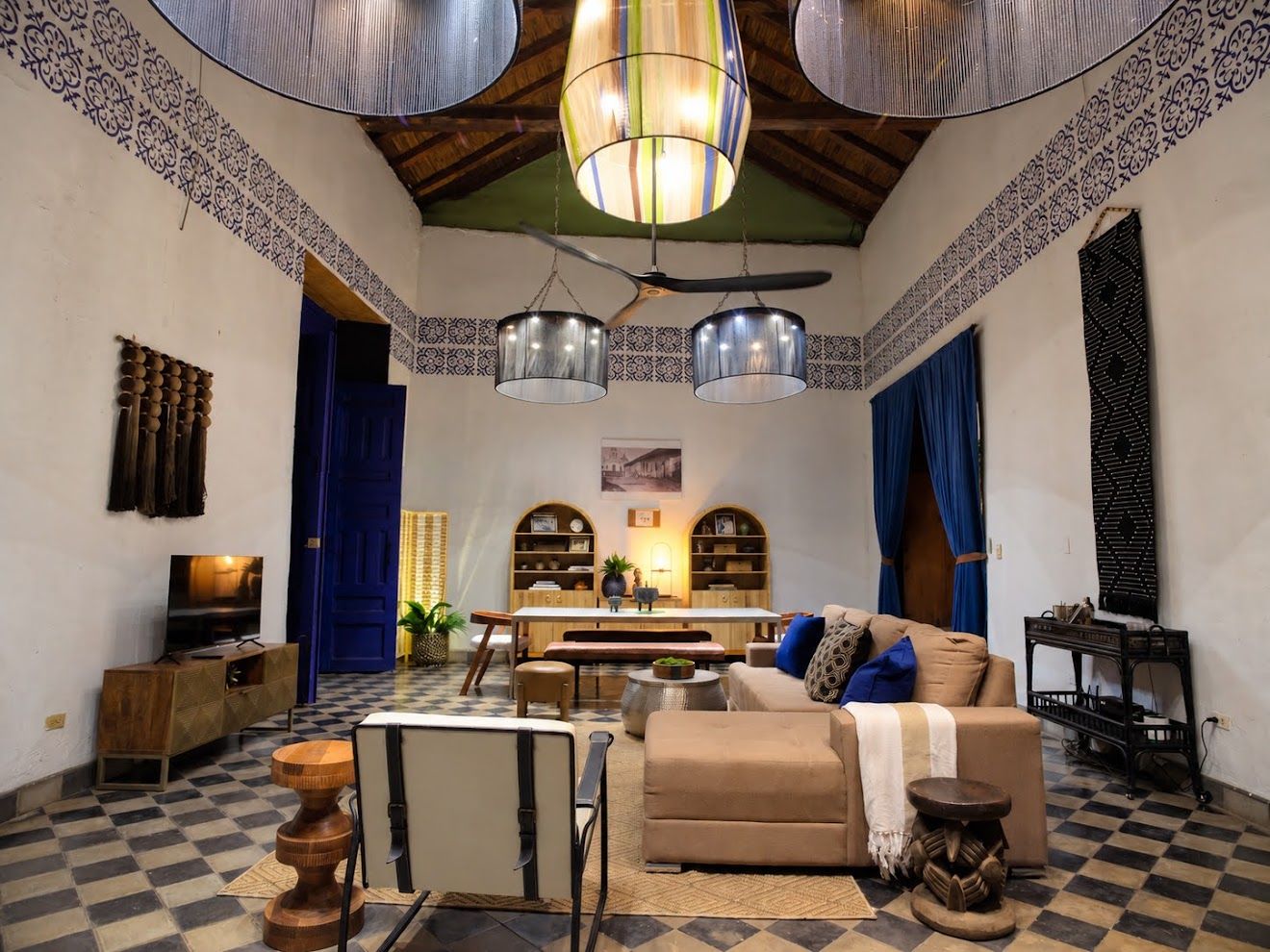 A cozy living room with a checkered floor, a sofa, a TV, and a dining area with a table and chairs.