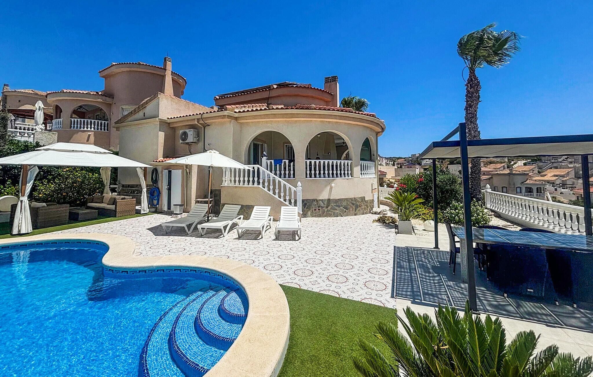 A poolside area with a swimming pool, lounge chairs, and a covered seating area.