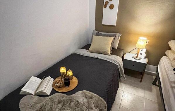 A bedroom with a bed, bedside table, lamp, and a book on the bed.