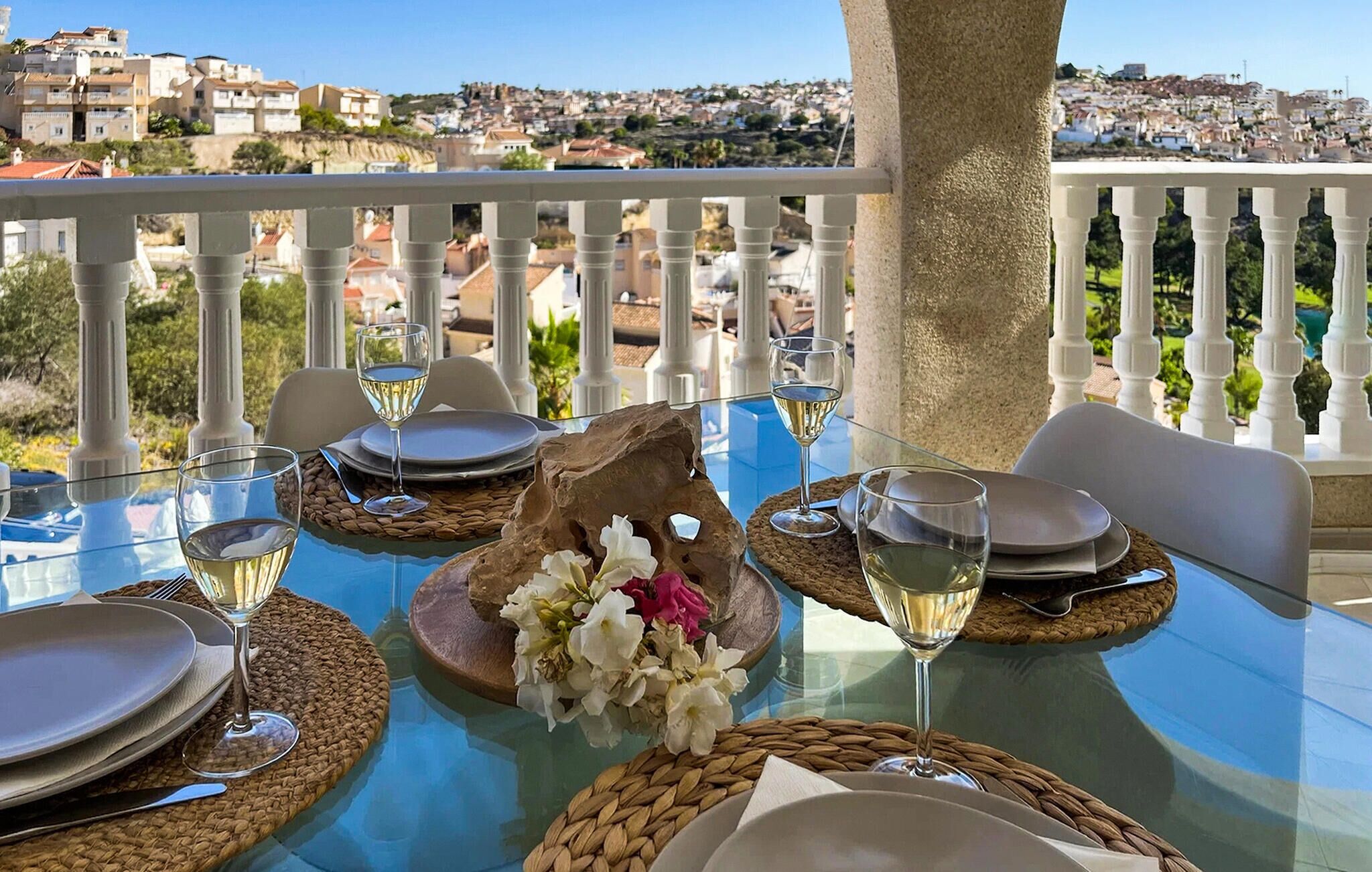 A table set for dining with a view of a coastal town.