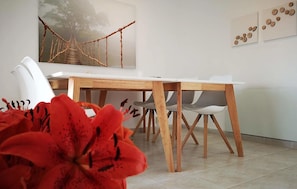 A dining area with a wooden table and white chairs, a painting of a bridge, and a wall with circular decorations. - Lovely home in Rojales with sauna (Rojales)