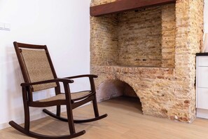 A rocking chair with a woven backrest and wooden frame, positioned in front of a stone fireplace with a wooden mantel. - History, Comfort & Character in Willemstad (Willemstad)