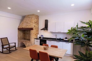 A modern kitchen with a brick oven, white cabinets, and a dining area with a wooden table and orange chairs. - History, Comfort & Character in Willemstad (Willemstad)