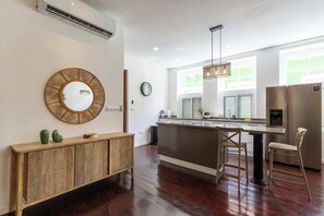 A modern kitchen with a wooden console, a round mirror, a clock, and a stainless steel refrigerator. - NEW | Beautifully Restored Historic Apartment (Willemstad)