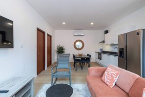 A compact living space with a kitchenette, a dining area, and a seating area with a sofa and a chair. - Elegant Apartment in Historic Punda (Willemstad)