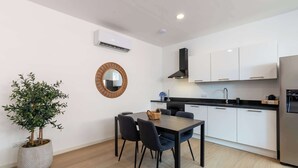 A modern kitchen with white cabinets, a black countertop, and a stainless steel refrigerator. - Elegant Apartment in Historic Punda (Willemstad)