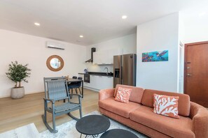 Una sala de estar moderna con un sofá, una mesa de comedor con sillas, una cocina y una planta en maceta.