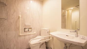 A modern bathroom with a marble wall, a white sink, and a toilet with a grab bar.