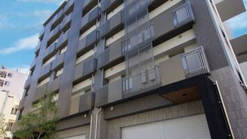 A multi-story building with a modern architectural design, featuring balconies on each floor and a garage door at the base.