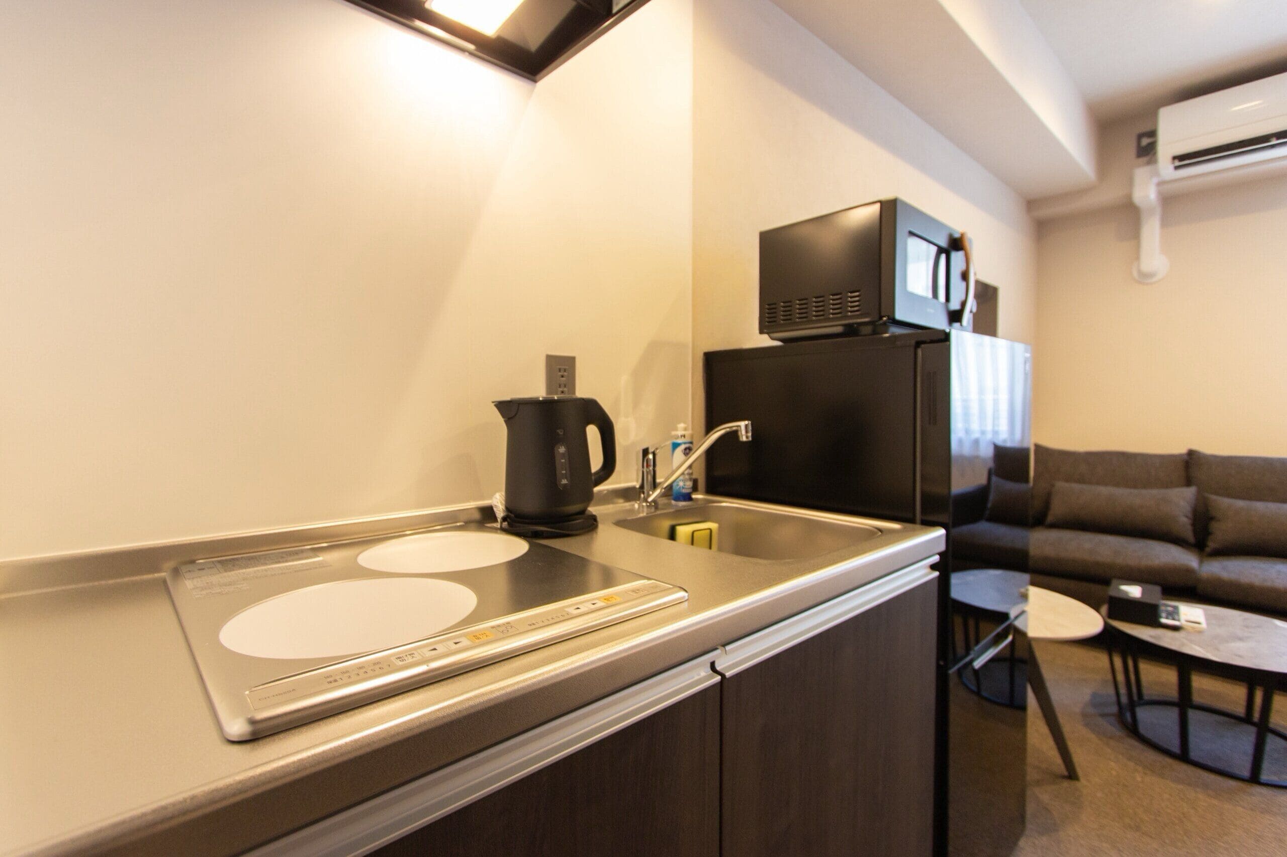 A modern kitchen with a built-in stove, a kettle, and a refrigerator.