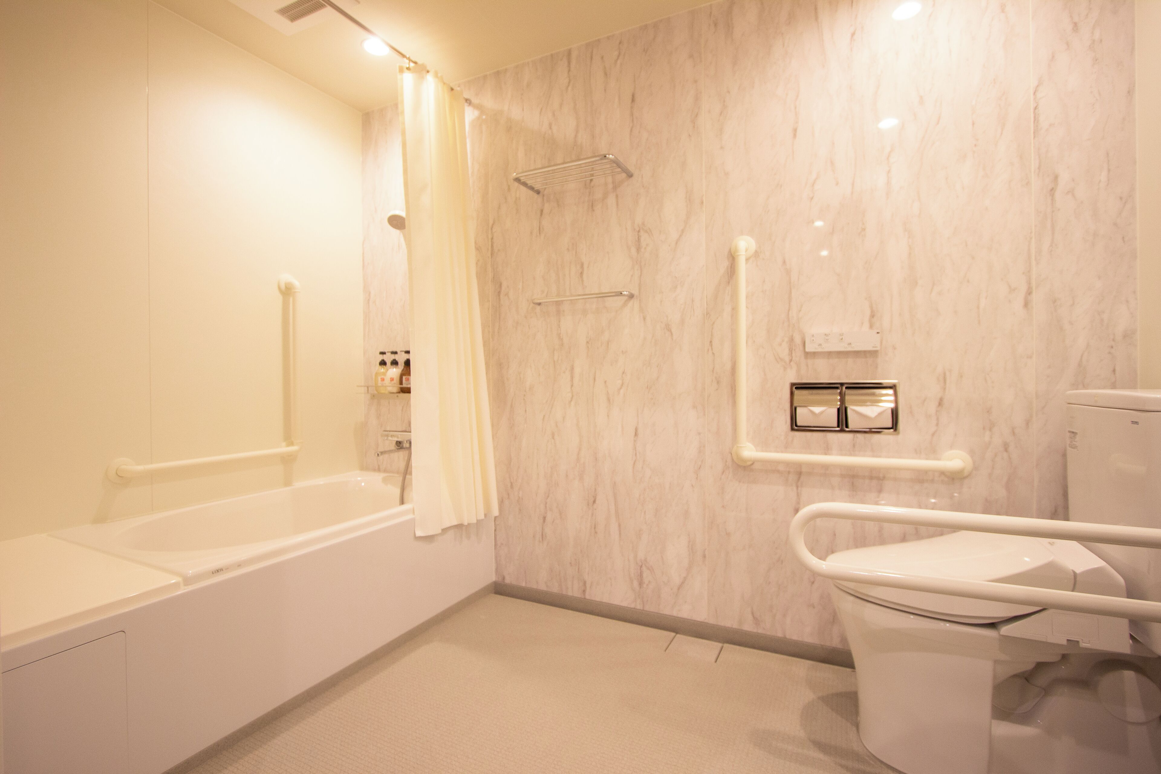 A bathroom with a bathtub, toilet, and grab bars.