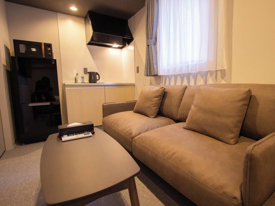A compact living space with a sofa, a coffee table, a kitchenette, and a TV.