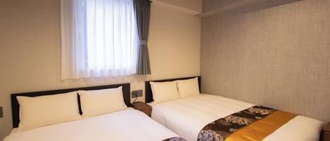 Habitación de hotel con dos camas, una ventana con cortinas y una pared lisa.