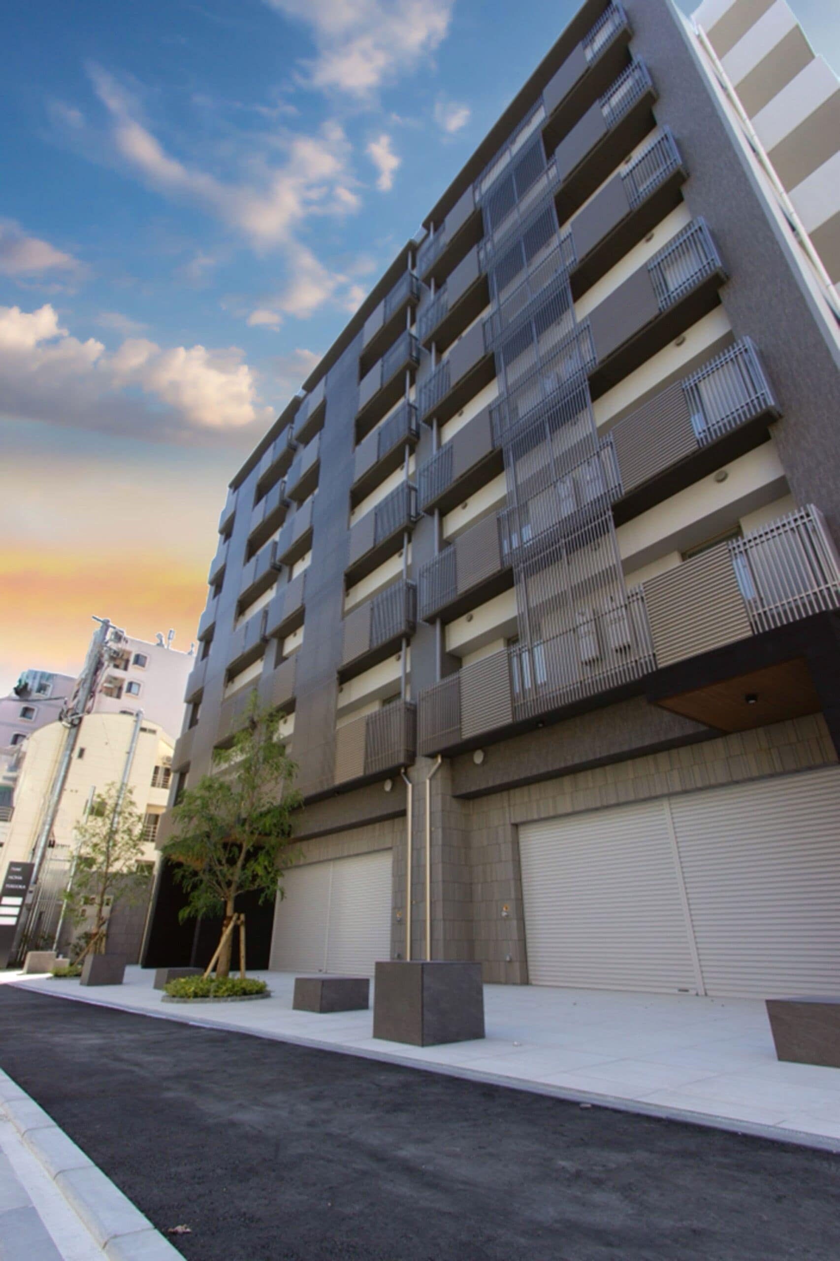A modern multi-story building with balconies, a garage door, and a clear sky.