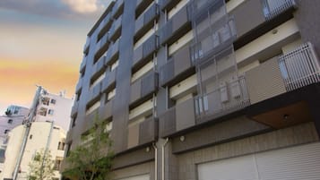 A modern multi-story building with balconies, a garage door, and a clear sky.