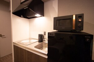 A compact kitchen with a microwave, a coffee maker, and a refrigerator.