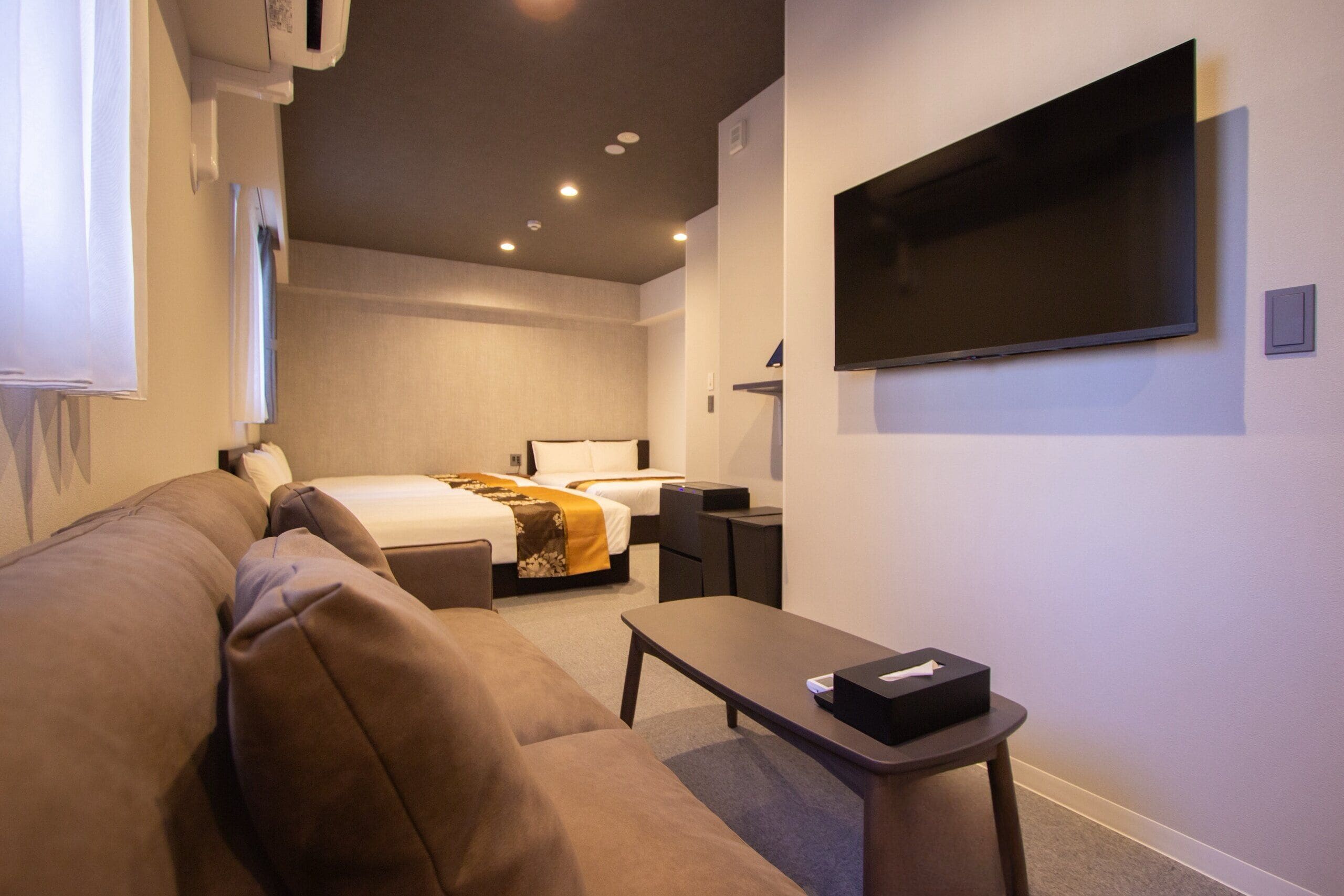 Une chambre d’hôtel équipée d’un lit, d’un canapé, d’un bureau et d’un téléviseur à écran plat fixé au mur.