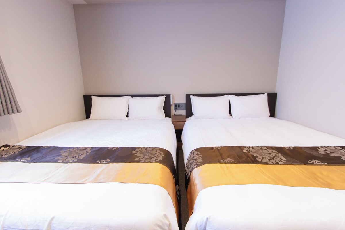 A hotel room with two single beds, each with a headboard and pillow.