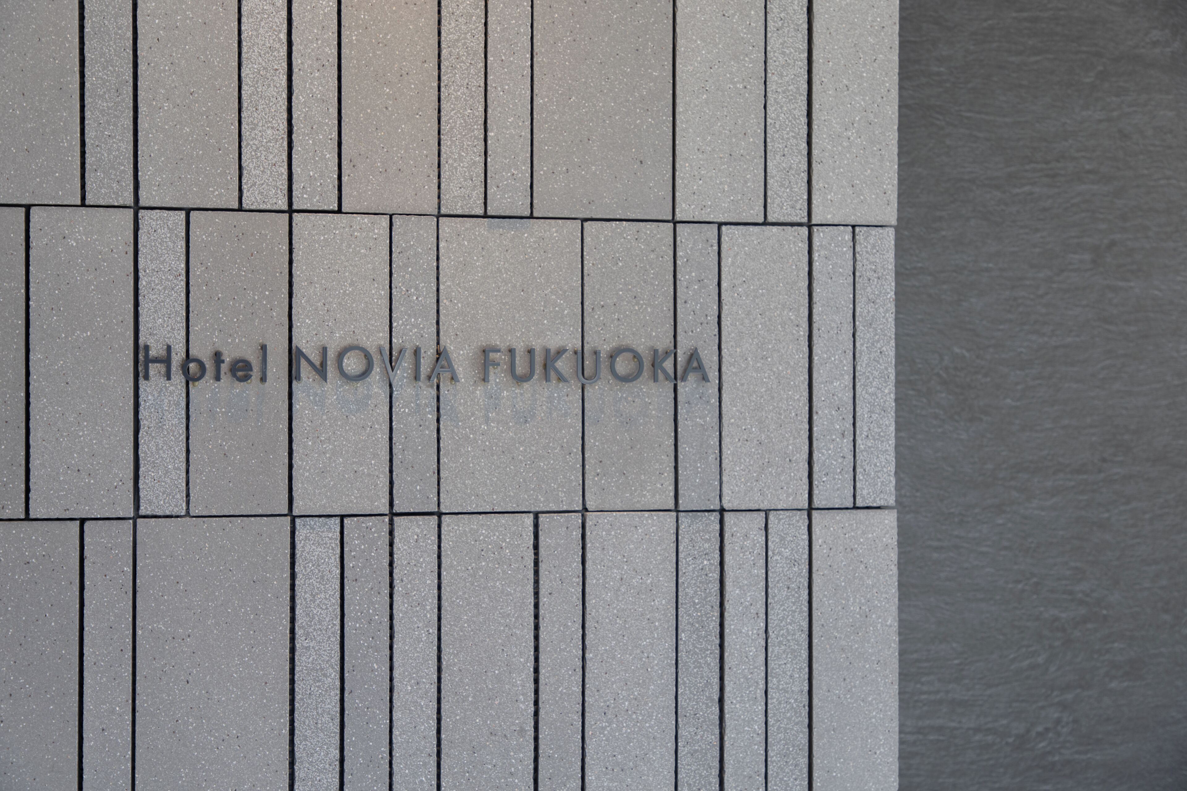 A tiled wall with the inscription 'Hotel NOVIA FUKUOKA' indicating the hotel's name.