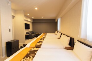Quarto de hotel com duas camas, um sofá, uma TV e uma escrivaninha.