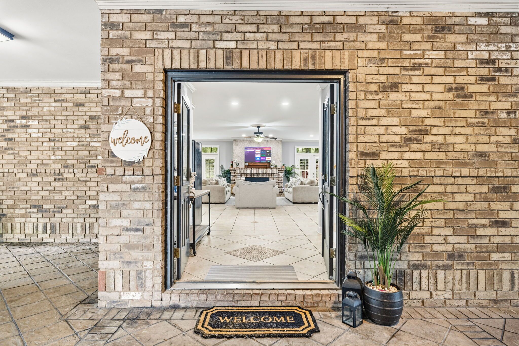 A brick-walled entrance with a welcome mat, a reception desk, and a television screen.