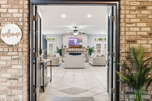 A spacious living area with a fireplace, sofas, a coffee table, and a television mounted on the wall. - Villa Bella - Luxury 4BR Home w/ Secluded Private Pool (Sleeps 16) (North Myrtle Beach)