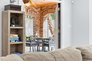 A room with a brick fireplace, a dining table with chairs, and a wooden bookshelf. - Villa Bella - Luxury 4BR Home w/ Secluded Private Pool (Sleeps 16) (North Myrtle Beach)