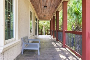 Une véranda avec un banc, un plafond en bois et une vue sur la verdure.