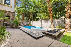A backyard with a swimming pool, patio furniture, and a brick barbecue area. - Villa Bella - Luxury 4BR Home w/ Secluded Private Pool (Sleeps 16) (North Myrtle Beach)