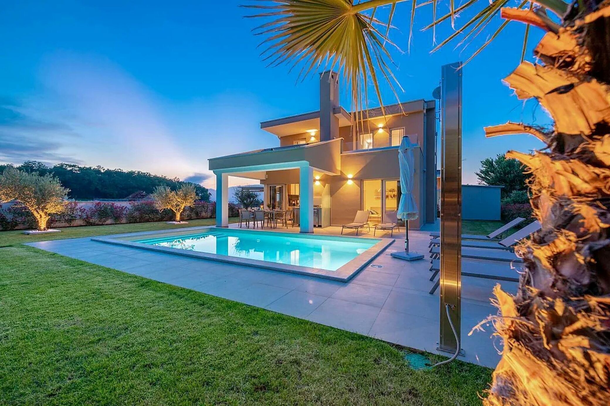 A modern house with a swimming pool, outdoor seating, and a well-lit patio area.