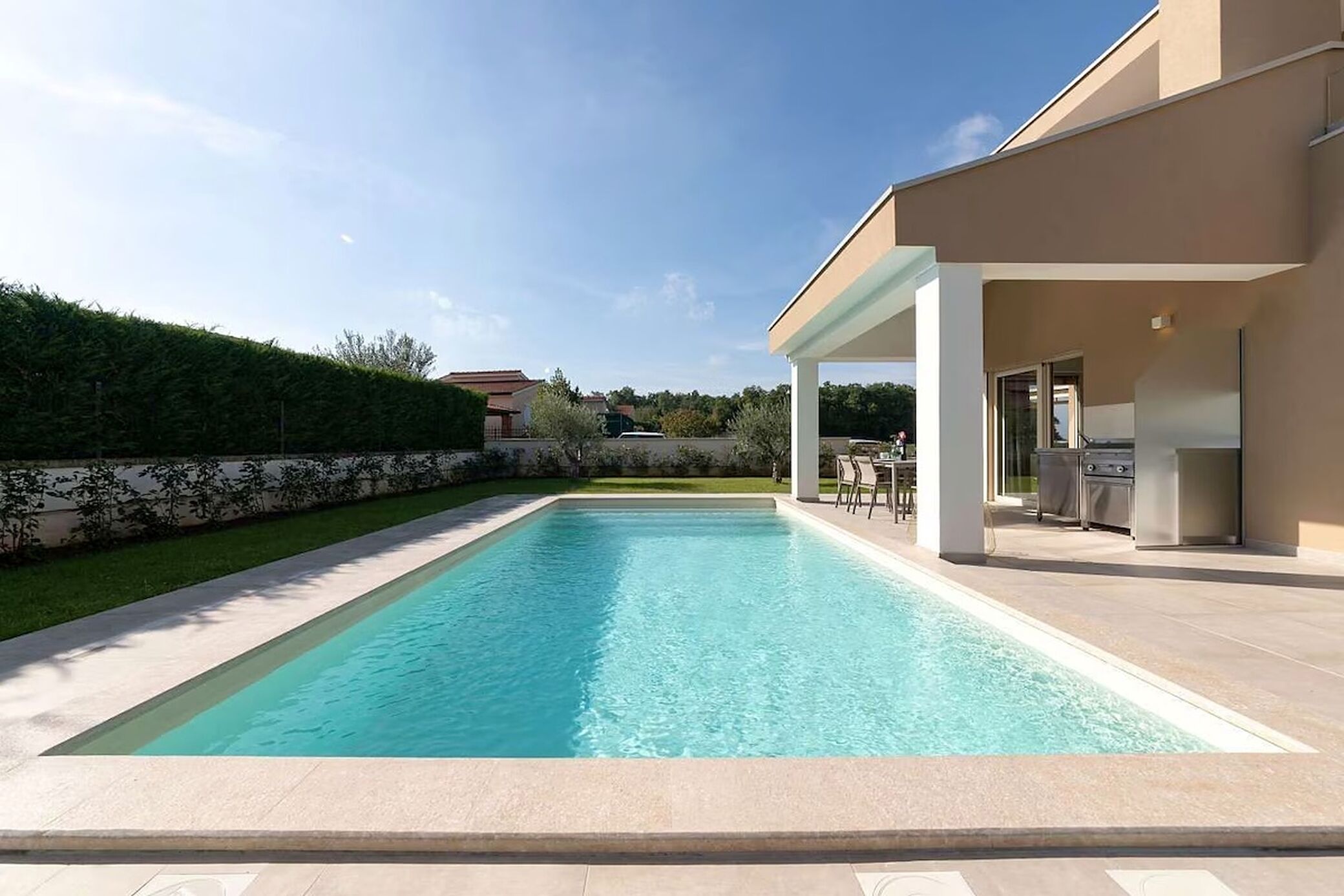 A rectangular swimming pool with a clear blue water surface, surrounded by a paved deck.