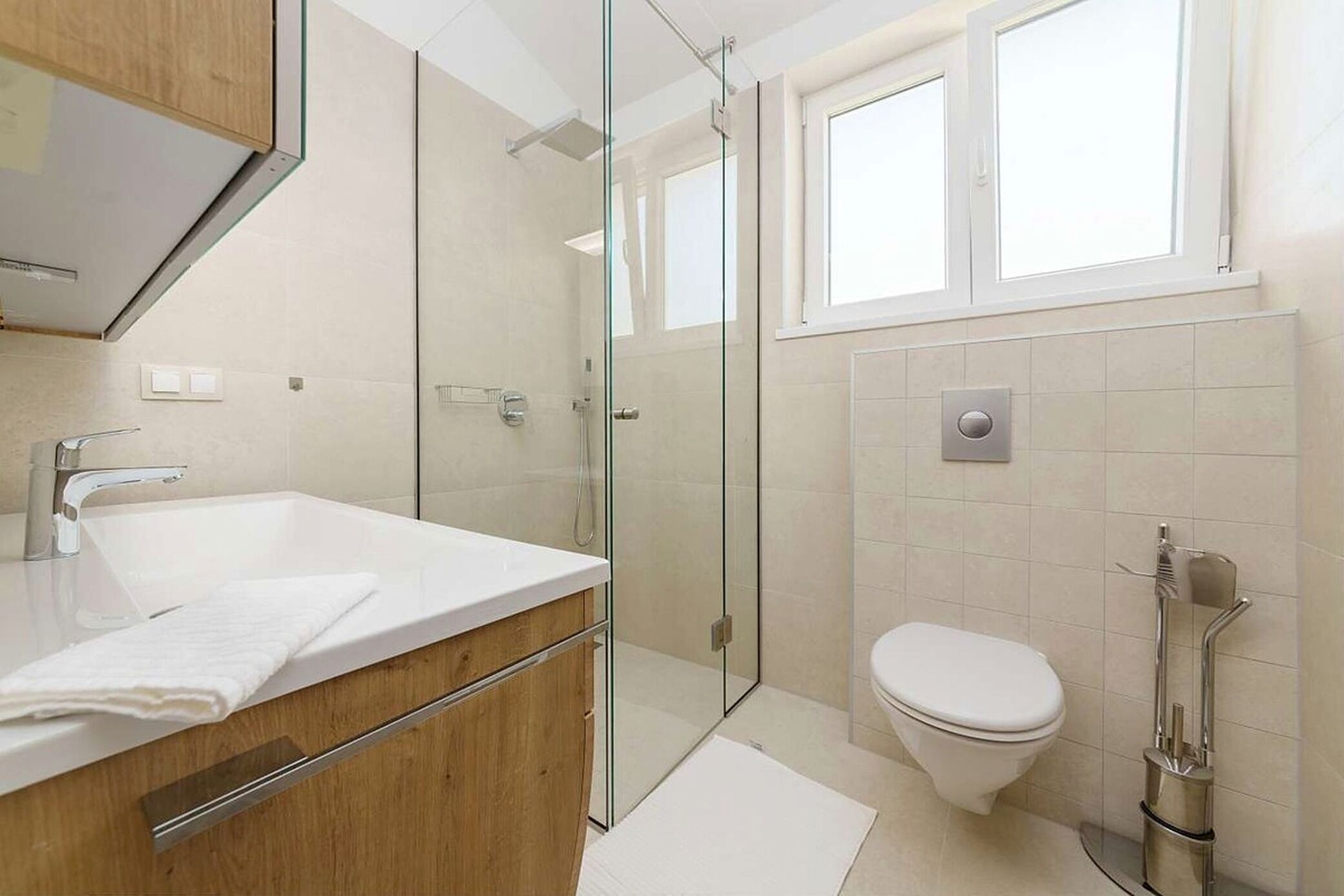 Une salle de bain moderne avec une douche à parois de verre, un lavabo blanc et des toilettes.