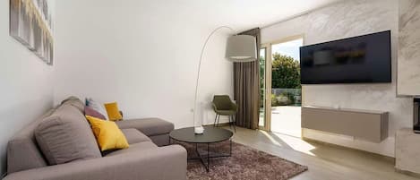 A modern living room with a sofa, a coffee table, and a TV mounted on the wall.