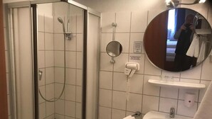 Une salle de bain avec une douche à parois de verre, un lavabo, un miroir et un porte-serviettes.
