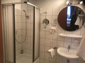 Une salle de bain avec une douche à parois de verre, un lavabo, un miroir et un porte-serviettes.