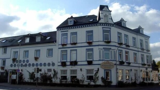 Un immeuble à étages, de style architectural classique, qui se distingue par son entrée d’angle imposante et ses nombreuses fenêtres.