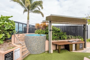 A hot tub with mosaic tiles, a pergola, a BBQ station, and a poolside area with artificial grass. - Central Located 1BR w/Parking | Near CBD and Transit (South Brisbane)