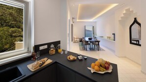 Eine moderne Küche mit Essbereich, Blick ins Freie und einer Treppe zu einer weiteren Ebene.