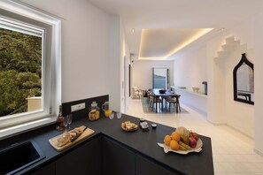 Eine moderne Küche mit Essbereich, Blick ins Freie und einer Treppe zu einer weiteren Ebene.