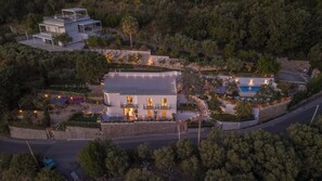 Una vila moderna amb piscina, envoltada de vegetació exuberant i un mur de pedra.