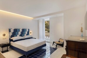 A modern bedroom with a large bed, a nightstand, a chair, and a view of the outdoors. - Villa Baia Serena, Panorama with Private Pool (Massa Lubrense)