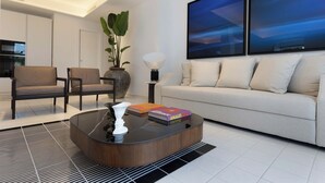 Ein modernes Wohnzimmer mit einer Couch, Sesseln, einem Couchtisch und einem großen Gemälde.