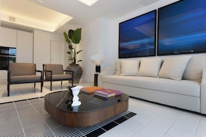 Ein modernes Wohnzimmer mit einer Couch, Sesseln, einem Couchtisch und einem großen Gemälde.